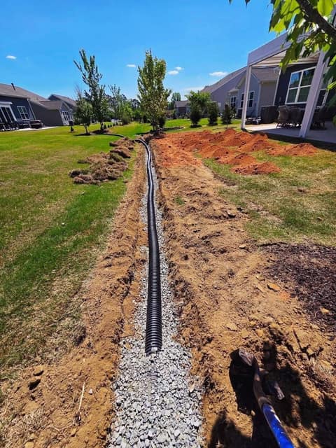 Corrugated drain pipe on a gravel bed running the length of the backyard