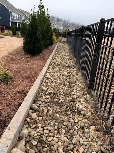 River-rock drainage channel through a lawn