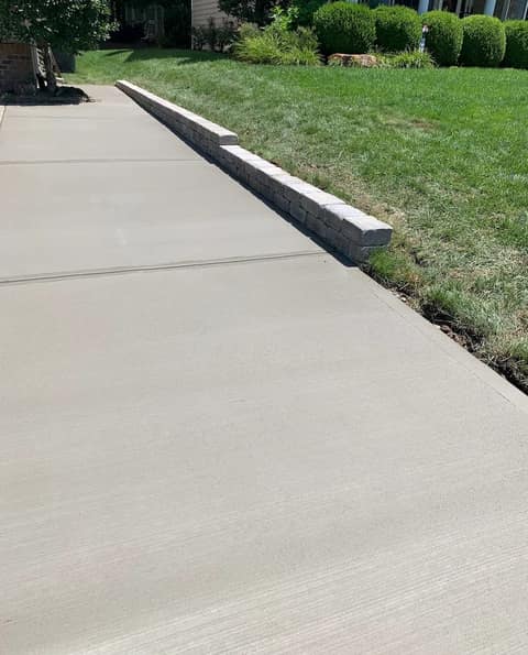 Freshly poured concrete driveway with a block edge along the lawn