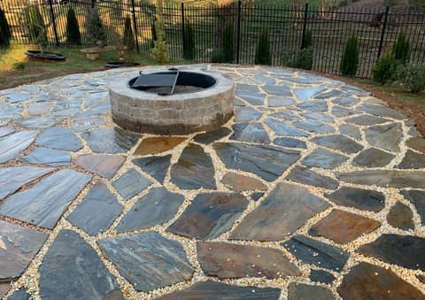 Flagstone patio set in pebble joints around a stone fire pit ring