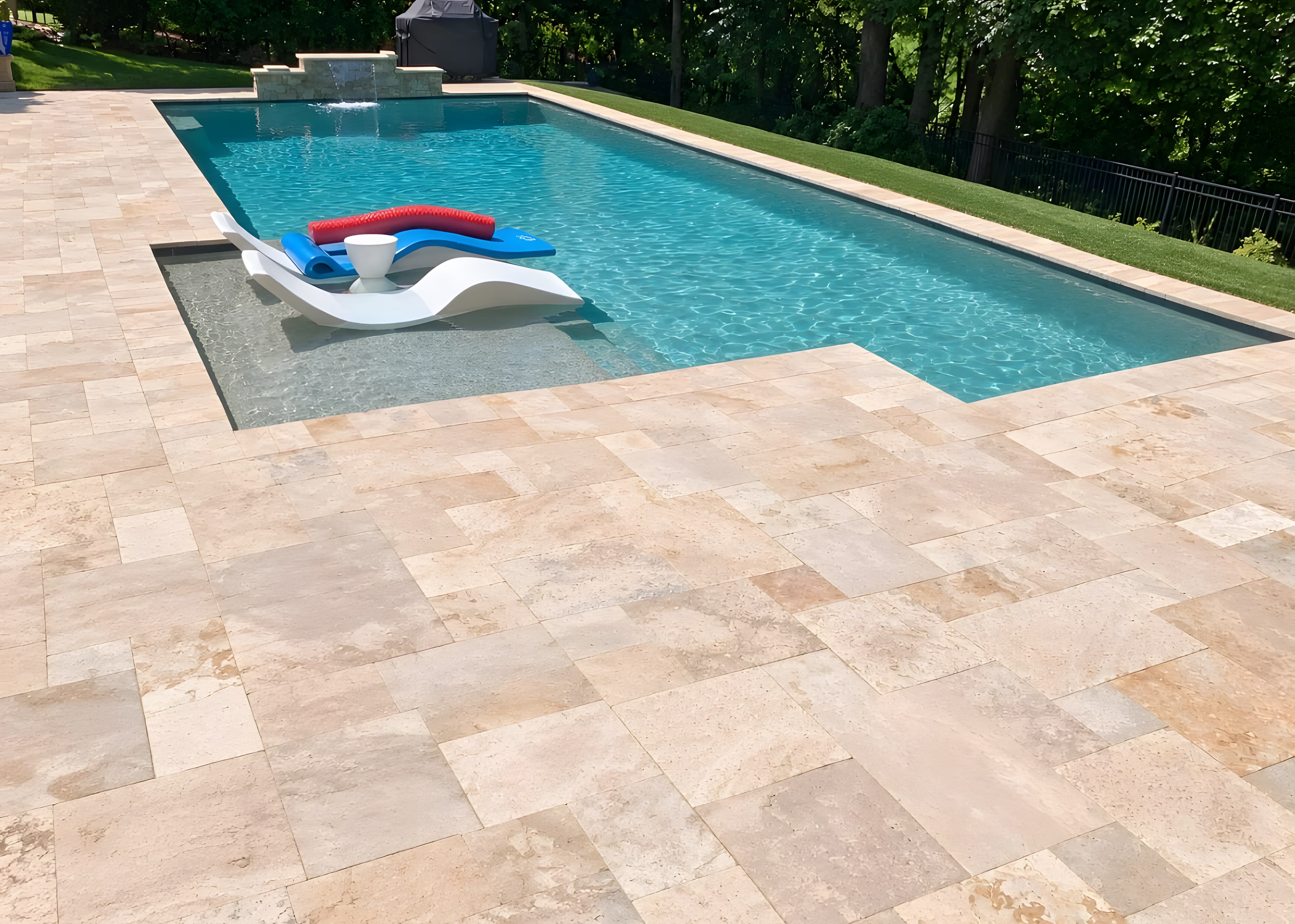 Travertine paver pool deck with a raised stone waterfall wall